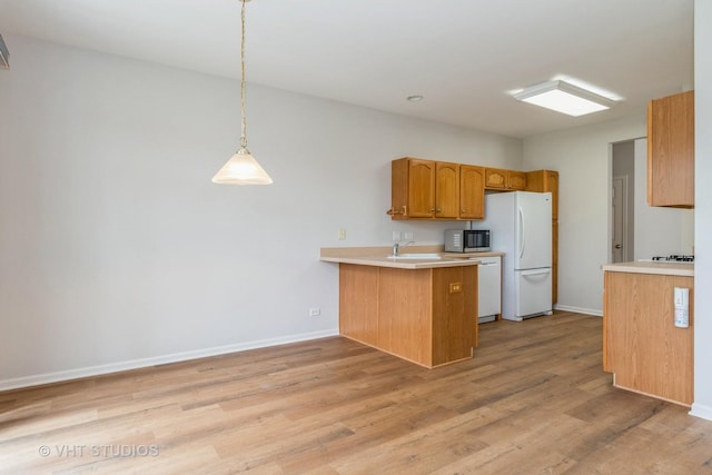 kitchen with a peninsula, baseboards, light wood-style floors, white appliances, and light countertops