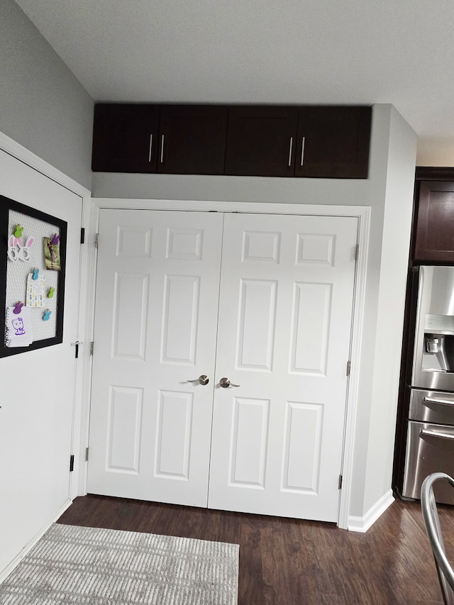 unfurnished bedroom featuring stainless steel refrigerator with ice dispenser, dark wood finished floors, and baseboards