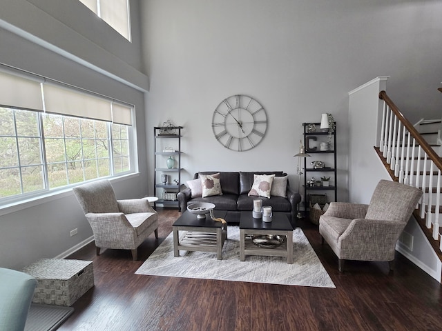 living room with a towering ceiling, wood finished floors, stairway, and baseboards