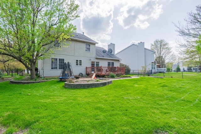 back of property featuring a lawn, a deck, fence, and a chimney