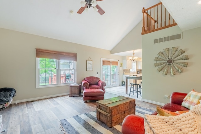 living room featuring visible vents, plenty of natural light, ceiling fan with notable chandelier, and light wood-type flooring