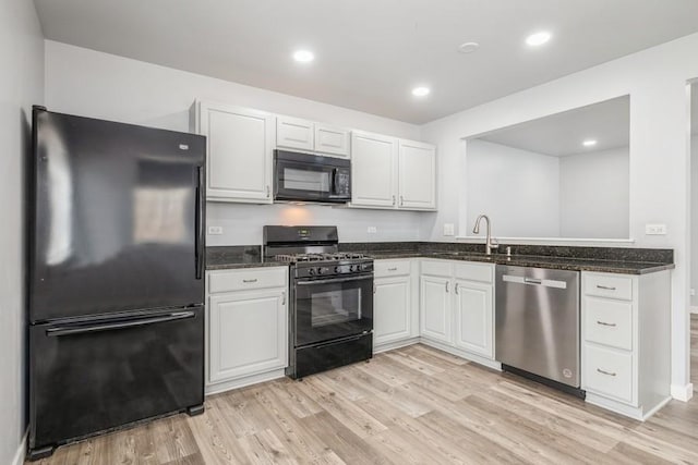 43 S Treehouse Ln, Round Lake, IL 60073 - kitchen with light wood-style flooring, dark stone countertops, white cabinetry, and black appliances