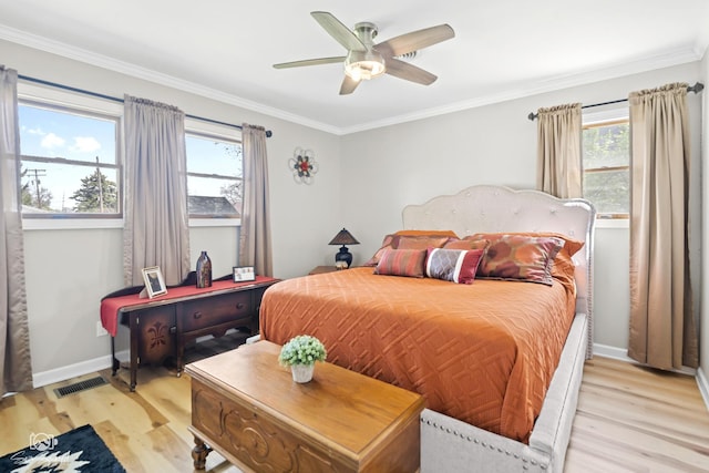 bedroom featuring light wood-style floors, crown molding, visible vents, and baseboards