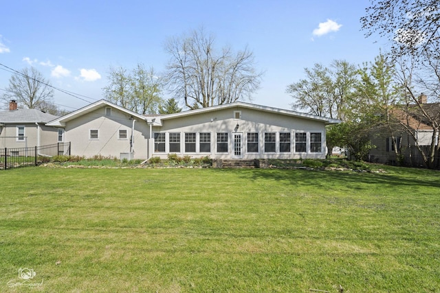 rear view of property featuring fence and a lawn