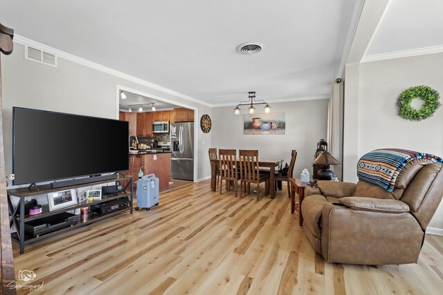 living area featuring visible vents, crown molding, light wood-style flooring, and baseboards