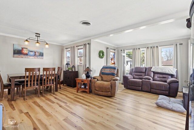 living area with visible vents, a healthy amount of sunlight, light wood-style floors, and crown molding
