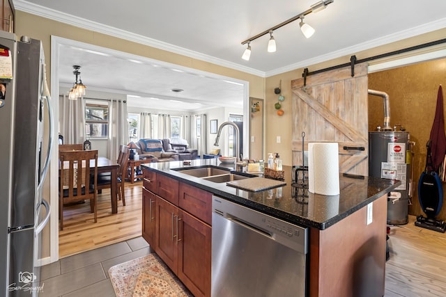 kitchen with gas water heater, a sink, a barn door, appliances with stainless steel finishes, and open floor plan