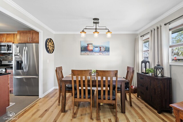 dining area with light wood-style floors, crown molding, and baseboards