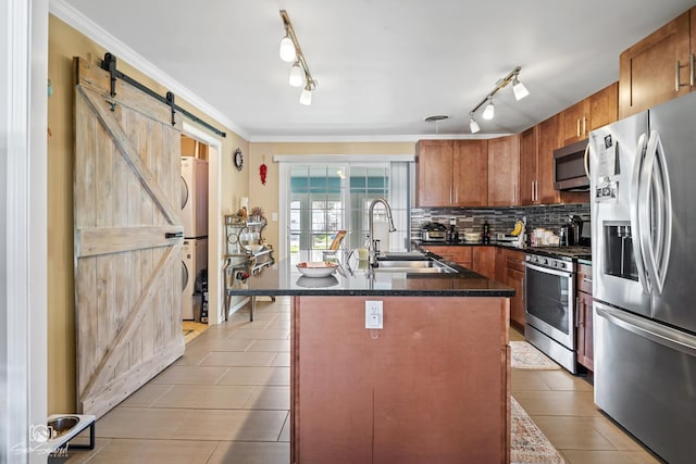 kitchen with decorative backsplash, rail lighting, appliances with stainless steel finishes, a sink, and stacked washing maching and dryer