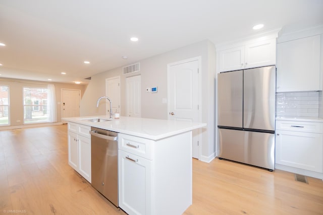kitchen featuring stainless steel appliances, visible vents, a sink, and light wood-style flooring