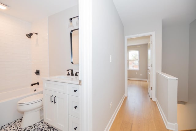 bathroom with vanity, toilet, wood finished floors, and shower / tub combination