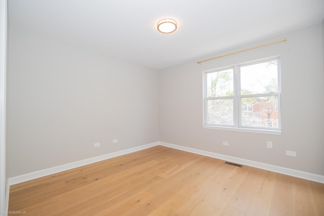 empty room with visible vents, baseboards, and light wood finished floors