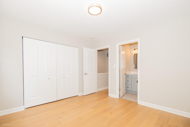 unfurnished bedroom with visible vents, a closet, baseboards, light wood-type flooring, and connected bathroom