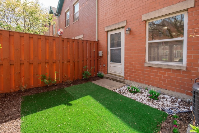 doorway to property with brick siding, fence, and a yard
