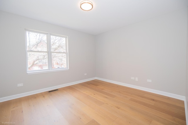 spare room with baseboards, visible vents, and light wood finished floors