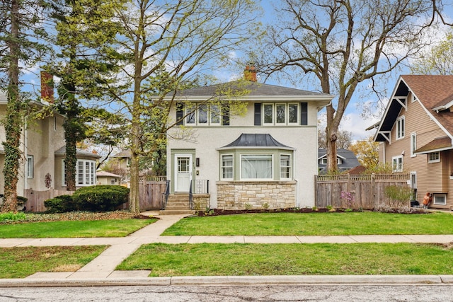 american foursquare style home featuring stucco siding, fence, a chimney, and a front yard
