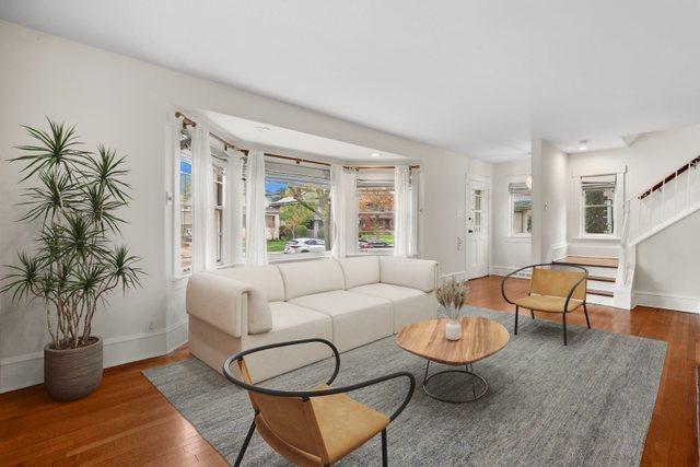living area featuring wood finished floors, baseboards, and stairway