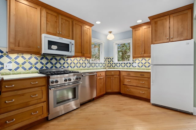 kitchen featuring brown cabinetry, decorative backsplash, stainless steel appliances, and light wood-style flooring