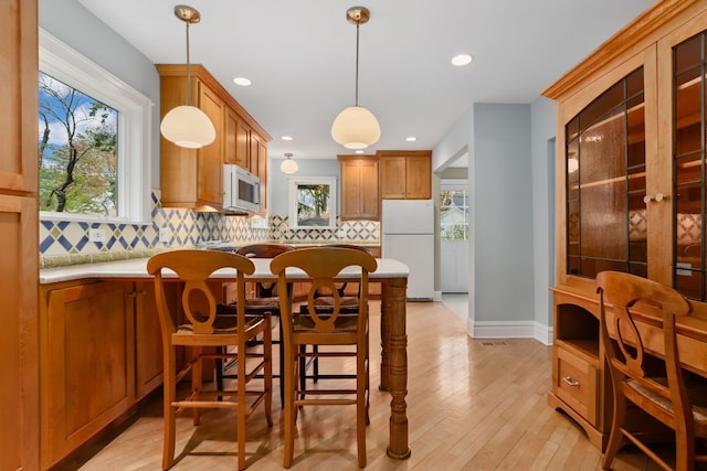kitchen featuring decorative backsplash, light countertops, white appliances, and a healthy amount of sunlight