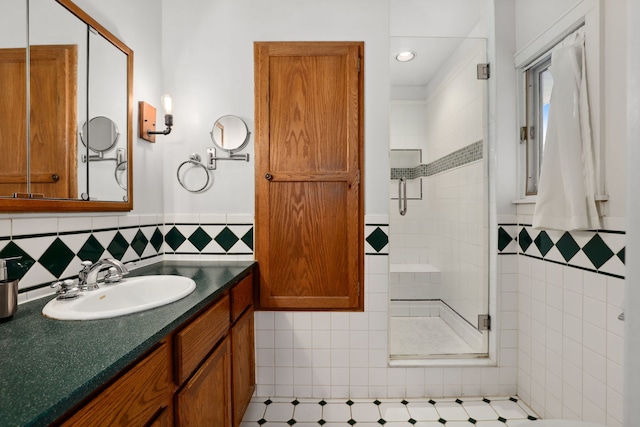 full bathroom featuring tile walls, wainscoting, vanity, and a shower stall