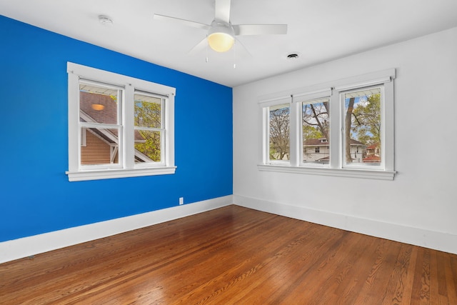 empty room with a ceiling fan, baseboards, a wealth of natural light, and dark wood-style flooring