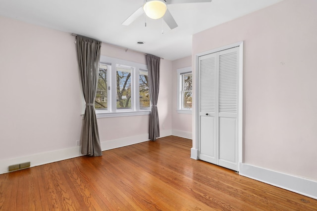 unfurnished bedroom with light wood-style flooring, baseboards, a closet, and a ceiling fan
