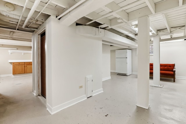 finished below grade area with baseboards and freestanding refrigerator