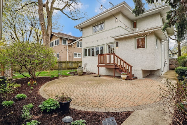 rear view of property with a patio, stucco siding, and fence