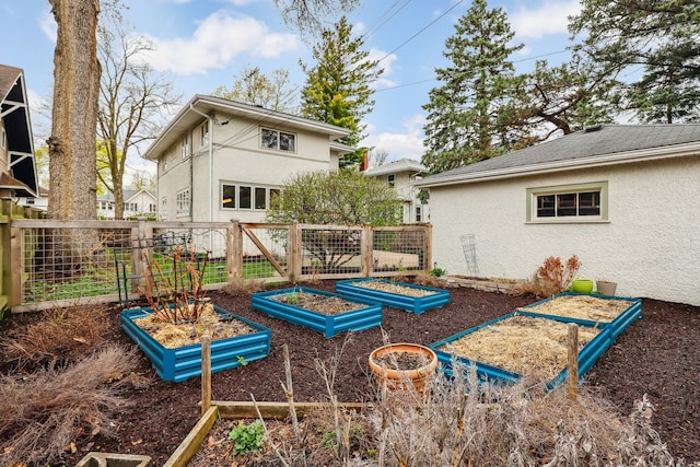 back of house featuring a garden, stucco siding, and fence