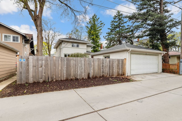view of home's exterior featuring an outdoor structure, fence, and driveway