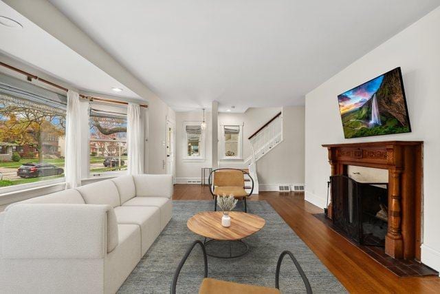 living area featuring stairs, wood finished floors, a fireplace, baseboards, and recessed lighting