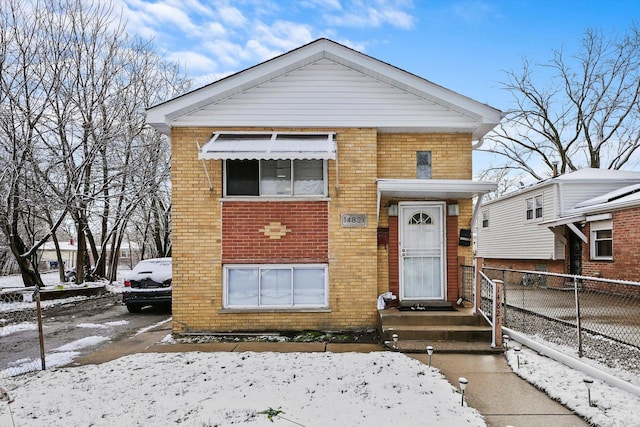 view of front of house featuring brick siding and fence