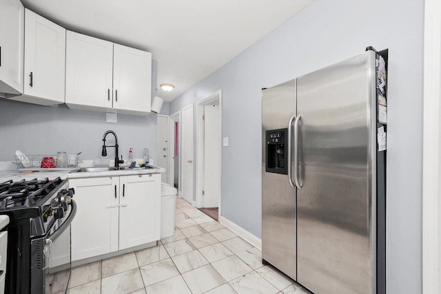 kitchen with a sink, stainless steel fridge, marble finish floor, black range with gas stovetop, and light countertops