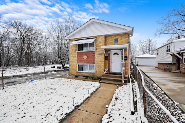 view of front of house with brick siding, fence, an outbuilding, and a detached garage