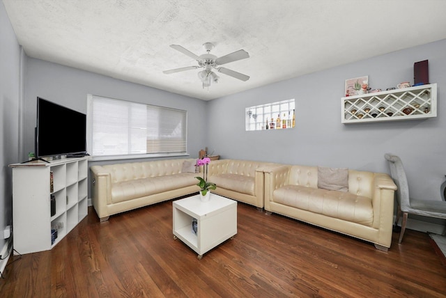 living area featuring a ceiling fan, a textured ceiling, and dark wood-style flooring