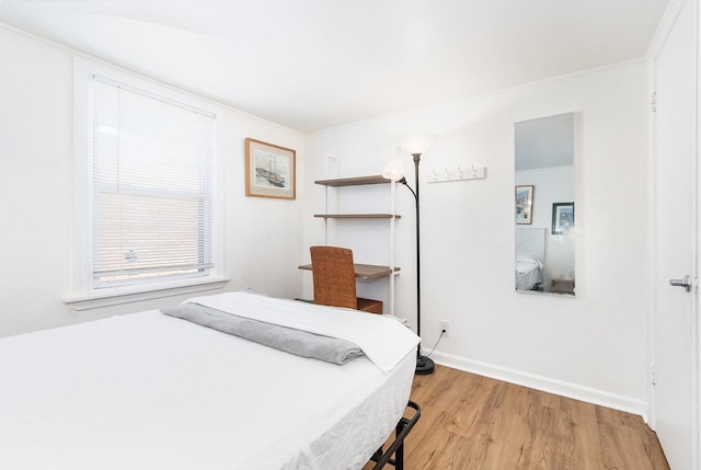 bedroom featuring light wood finished floors and baseboards