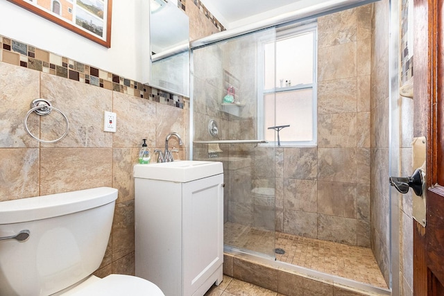 full bath with toilet, tile walls, a shower stall, and vanity