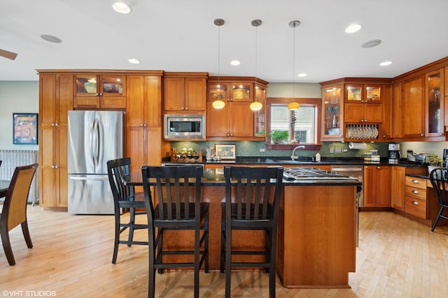 kitchen featuring brown cabinets, light wood-style flooring, appliances with stainless steel finishes, and a center island