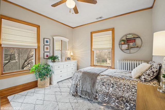 bedroom featuring radiator heating unit, visible vents, crown molding, and multiple windows