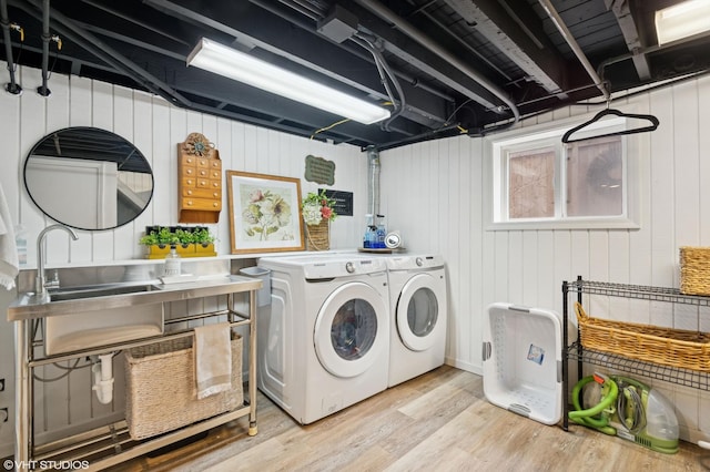 laundry room with wooden walls, light wood-type flooring, washer and dryer, and laundry area