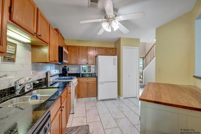 kitchen featuring visible vents, brown cabinetry, marble finish floor, white appliances, and a sink