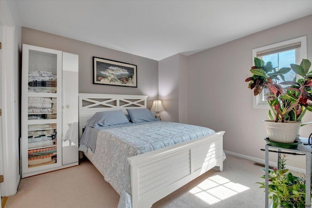bedroom featuring baseboards, visible vents, and light colored carpet