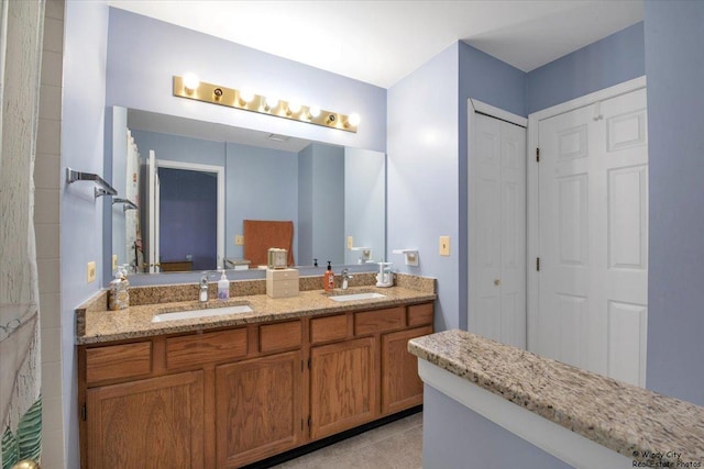 full bath featuring double vanity, a sink, and tile patterned flooring