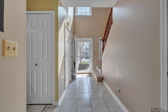 foyer entrance with baseboards, marble finish floor, and stairs