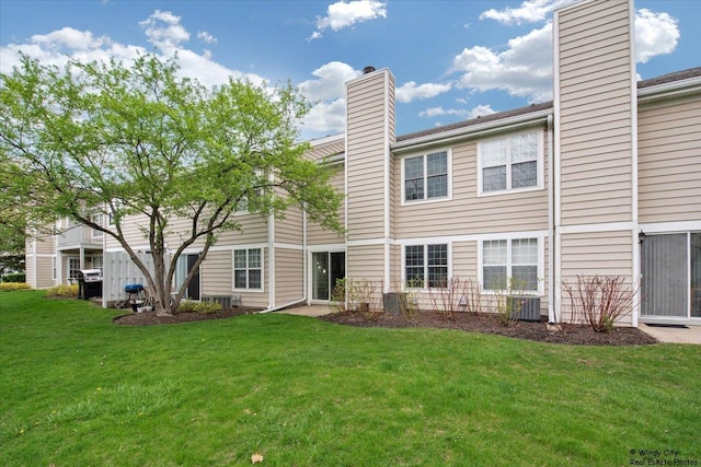 back of property featuring a lawn, central air condition unit, and a chimney