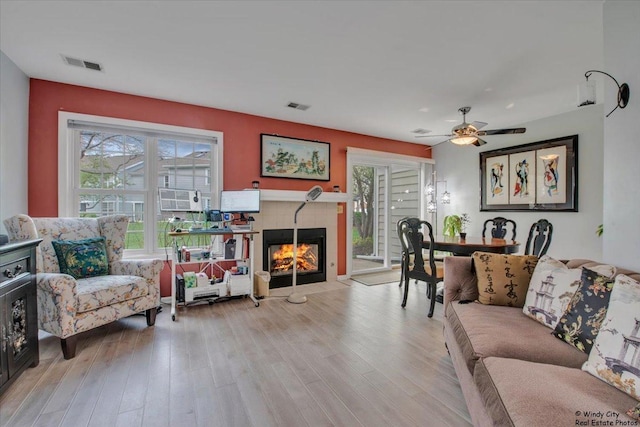 living area featuring visible vents, plenty of natural light, and a tile fireplace