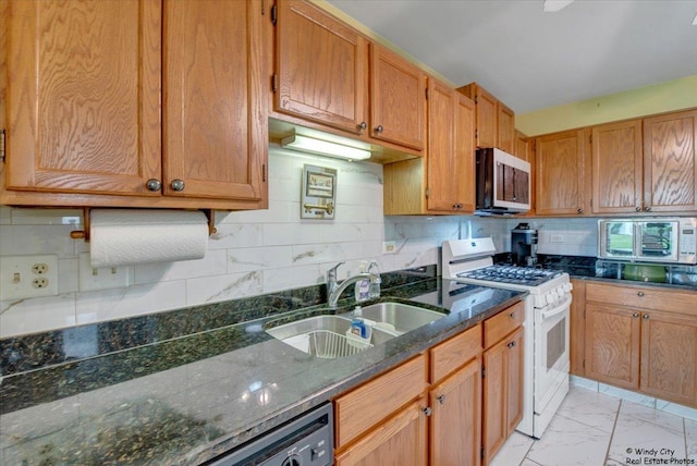kitchen with white gas range oven, a sink, marble finish floor, dark stone countertops, and decorative backsplash