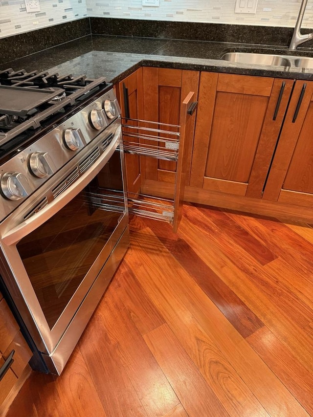 651 N Milwaukee Ave Unit 403, Chicago, IL 60642 - details featuring stainless steel range with gas stovetop, a sink, backsplash, and brown cabinets