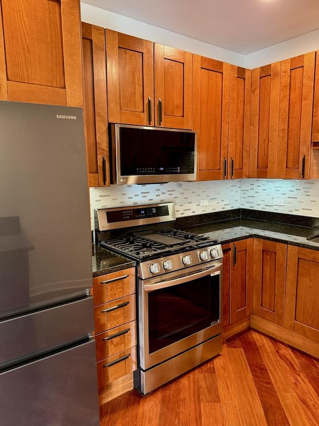 651 N Milwaukee Ave Unit 403, Chicago, IL 60642 - kitchen featuring brown cabinets, appliances with stainless steel finishes, wood finished floors, and tasteful backsplash