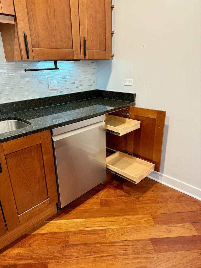 651 N Milwaukee Ave Unit 403, Chicago, IL 60642 - kitchen with dark stone countertops, decorative backsplash, light wood-type flooring, dishwasher, and brown cabinetry
